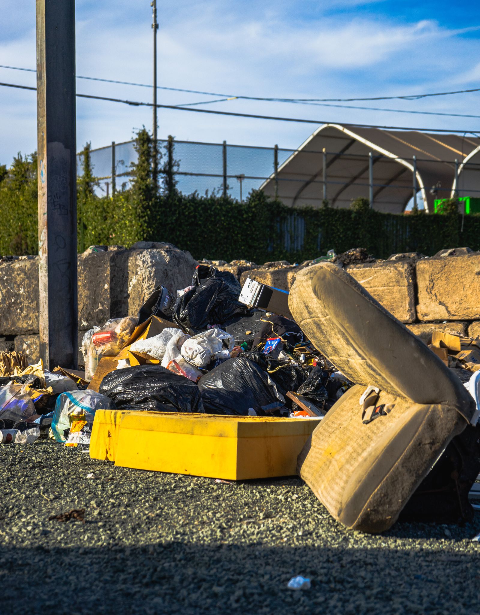 A mattress and bagged rubbish piled beside a container