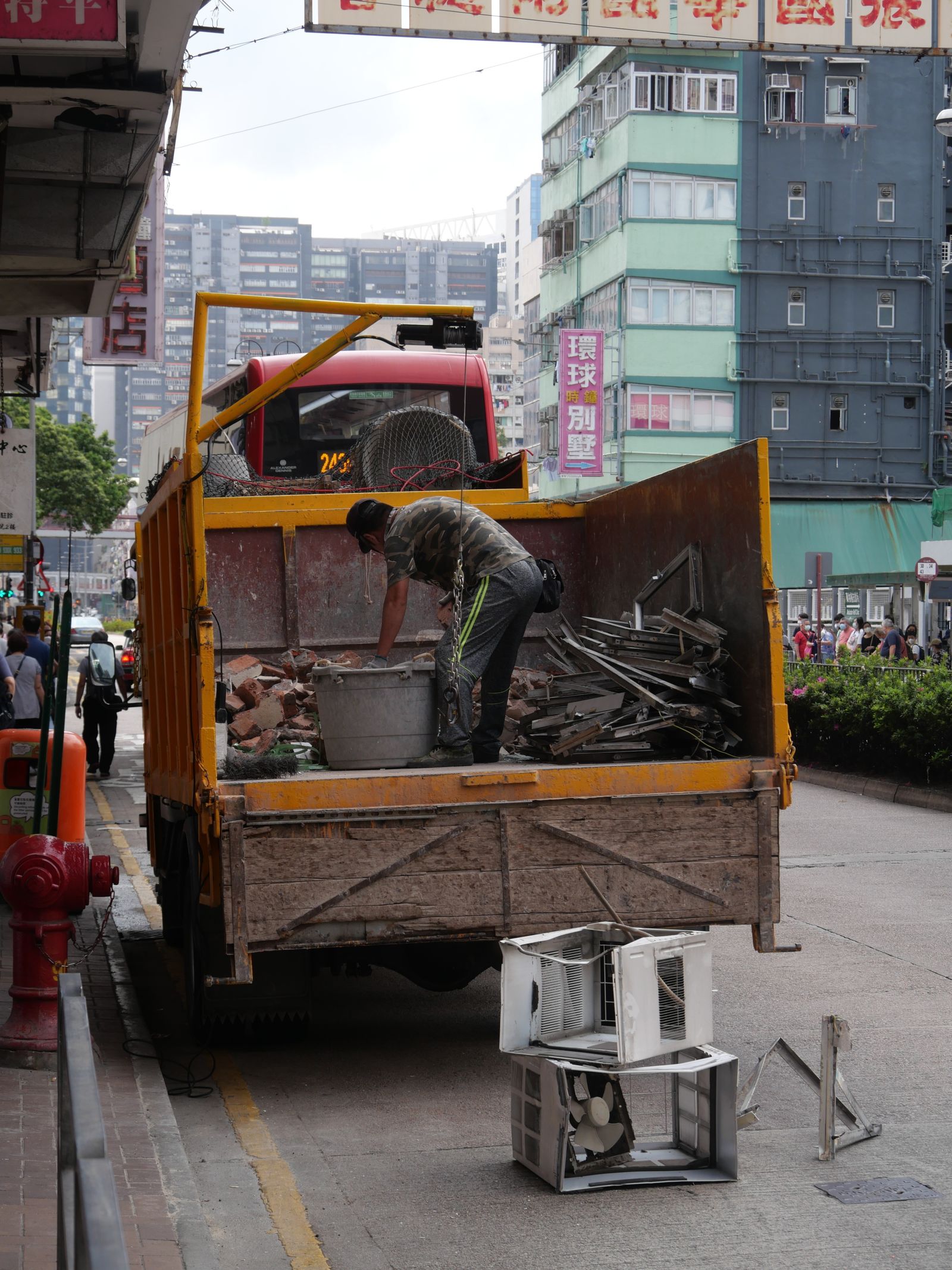 A worker sorting debris in the bed of a dump truck